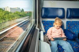 Beautiful Little girl using digital tablet during traveling by railway in Germany, Europe photo