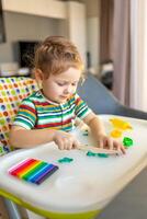 Little girl plays with multi-colored plasticine, creates different shapes photo