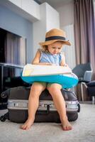 Little girl with suitcase baggage luggage and inflatable life buoy reading map and ready to go for traveling on vacation photo
