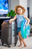 Little girl with suitcase baggage luggage and inflatable life buoy ready to go for traveling on vacation photo