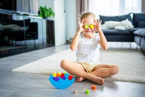 Little girl playing with wooden balancing toy on the floor in home living room. photo