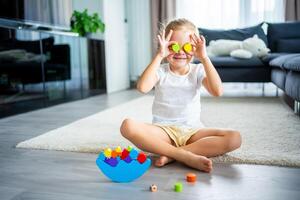 Little girl playing with wooden balancing toy on the floor in home living room. photo