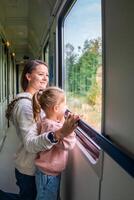 familia de viaje en un tren y mirando mediante ventana. mujer con niño de viaje por ferrocarril en Europa foto