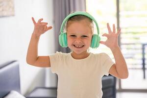 Portrait of little girl listening to the music with kids headphones and dancing at home in happy morning. High quality photo