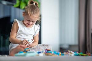 Smiling Little girl playing with small constructor toy on the floor in home living room, educational game, spending leisure activities time concept photo