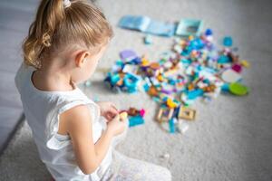 Little girl play with constructor toy on floor in home, educational game, spending leisure activities time concept. Focus on child photo