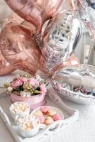 flores y dulces en blanco mesa y globos en el blanco cama. regalo para San Valentín día o marzo 8 o de la madre día o cumpleaños. alto calidad foto