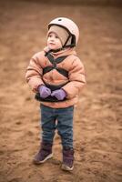 retrato de pequeño niña en protector chaqueta y casco antes de montando lección. alto calidad foto