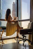 Stylish businesswoman freelancer working with laptop and sitting on table, enjoying panoramic view in city background. Low key photo. High quality photo