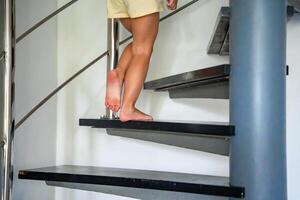 Close up view of little child feet going up the stairs at modern home, child climbing spiral staircase photo