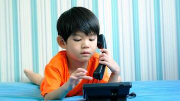 A little Asian boy is filming an online video outdoors while going to the beach.