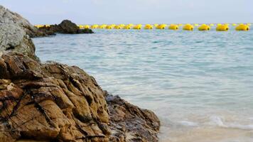 bellissimo visualizzazioni di il spiaggia, mare, rocce durante il giorno con boe separare il nuoto la zona. video