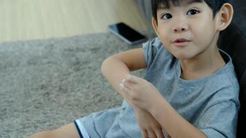 Little Asian boy's hands peeling off dry skin on his legs. Skin problems. video