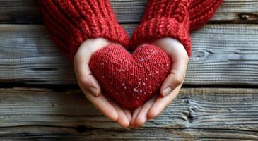 ai generado manos en rojo suéter y rojo corazón en de madera antecedentes foto