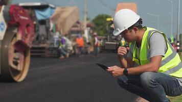 Asian engineers watch road rebuilding workers and asphalt machines of the road at the construction site. video