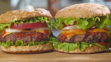 Frais appétissant du boeuf des hamburgers sur le cuisine tableau. délicieux Burger avec Frais iceberg chou, oignons, tomates et grillé steak. vite nourriture, Piste caméra mouvement, 4k video