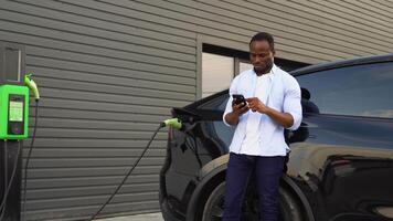 africano americano hombre cargando eléctrico coche a estación video