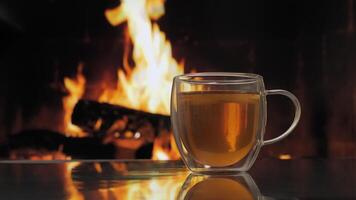 vidro caneca com fruta chá contra fundo do uma lareira com uma chama. fresco quente ervas chá com hortelã e laranjas, desintoxicação bebida. video