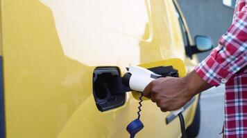 onherkenbaar zwart Mens haalt de stekker uit het stopcontact opladen kabel elektrisch voertuig. groen energie, eco vriendelijk brandstof. mannetje hand- verbreekt de verbinding macht connector in ev auto video