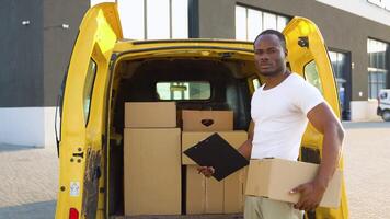 africano americano Corriere con appunti e scatola vicino consegna furgone all'aperto video