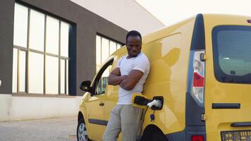 afrikansk amerikan deliveryman på elektro laddning station nära frakt elektrisk bil video