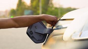 Black man disconnects power connector into cargo EV car, close up video