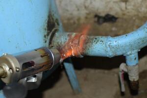 Heating a steel pipe with a blowtorch. The flame of a blowtorch photo