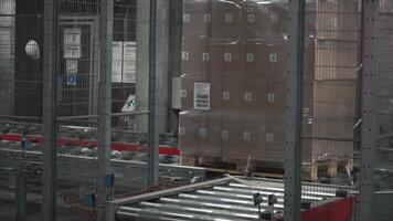 Moving conveyor belt with cardboard boxes along corridor in workplace. Clip. Boxes move along conveyor belt. Cardboard boxes picked up by a robot arm in a factory video