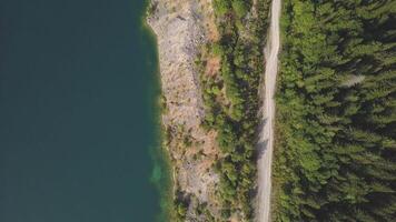 Amazing aerial drone shot road along a lake. Clip. Pond and road in mountains top view video