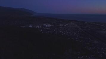 Nacht Panorama von das Stadt von Sotschi von ein Vogel Auge Sicht. Clip. Panorama von Sotschi von das Luft. Häuser, Straßen, Bäume, das Nacht Himmel sind sichtbar. im das Entfernung Sie können sehen das Meer. Sotschi, Russland video