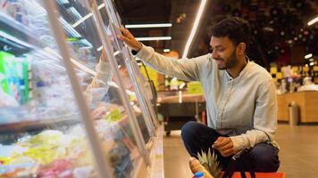 lado ver de hermoso indio hombre comprando queso. un hombre compras queso en tienda de comestibles Tienda video