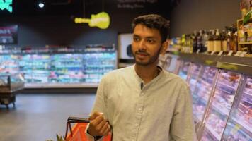Indisch Mens wandelen in gangpad met zijn troel Bij supermarkt. jong Mens boodschappen doen in kruidenier op te slaan video