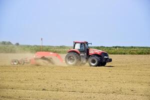 tractor con un calificador alinea el suelo en el campo. el tractor elevado polvo. foto