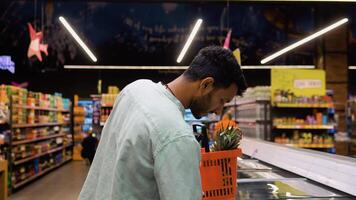 Indisch Mens boodschappen doen voor bevroren vis zeevruchten in supermarkt kleinhandel op te slaan video