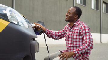 African american male disconnects power connector into EV car video