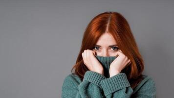 shy or embarrassed woman pulling turtleneck sweater over face photo
