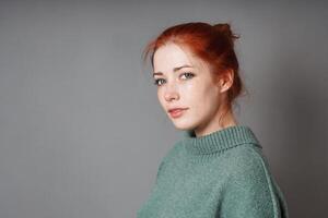 young woman with red hair bun and roll neck pullover photo