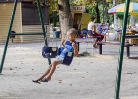 The little boy swings on the swing himself. photo