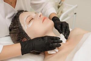 A close-up cosmetologist cleanses the client's skin with cotton pads. photo