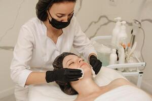 The cosmetologist cleanses the client's skin with cotton pads. photo