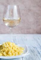 Portion of risotto with glass of white wine photo