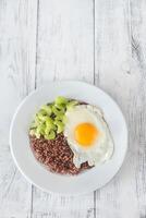 Portion of red quinoa with fried egg and celery photo