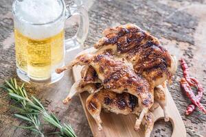 A la parrilla codornices con vaso de cerveza foto