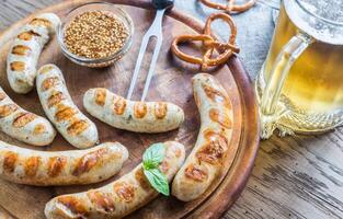 A la parrilla salchichas con pretzels y jarra de cerveza foto