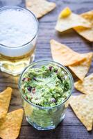 Guacamole with tortilla chips and glass of beer photo