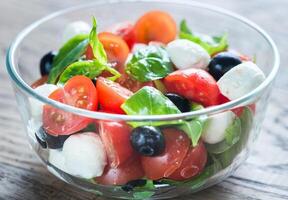Salad with tomatoes, olives, mozzarella and basil photo