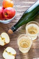 Bottle and two glasses of cider on the wooden background photo