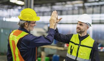 ingenieros sacudir manos después completando trabajo en un pesado maquinaria fábrica foto