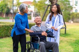 Senior man on wheelchair with doctor and wife photo