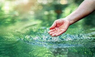 hand touches water in the pond photo